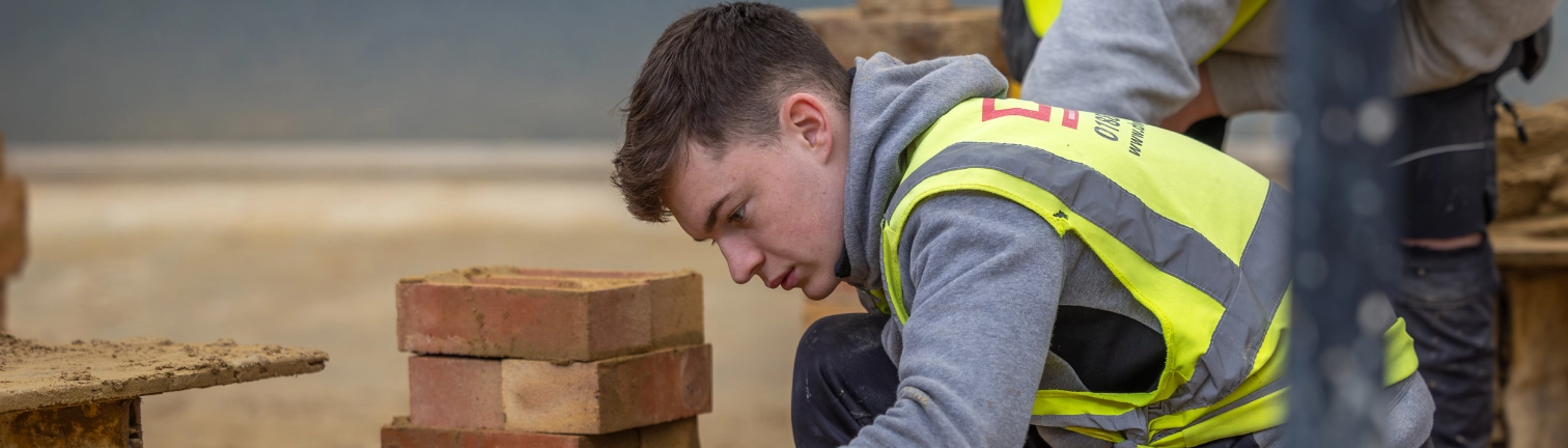 Bricklaying students lays a cavity wall in the workshop