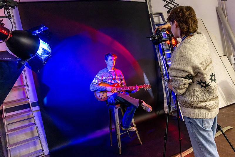 Student taking photo of another student in a studio