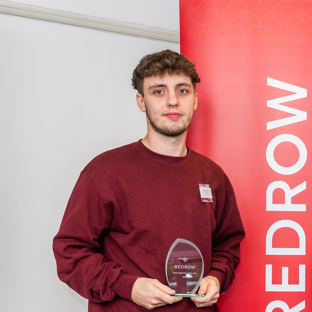 Keiron with his award smiling at the camera with his employer