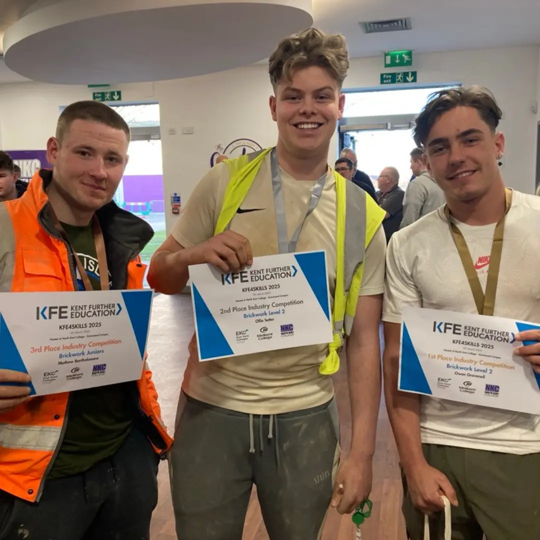 Three construction students with their winning certificates smiling at the camera